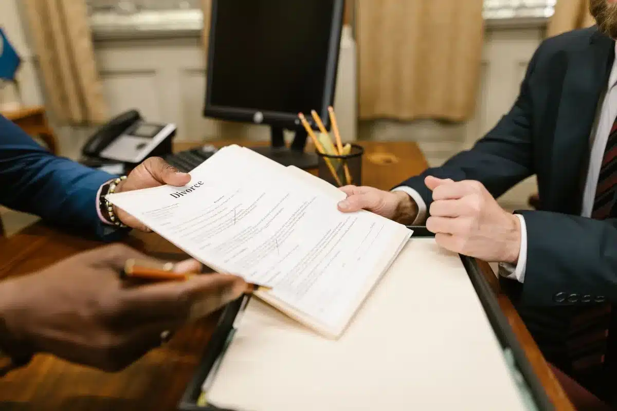 Mains anonymes signant des documents officiels avec tampons et dossier sur un bureau