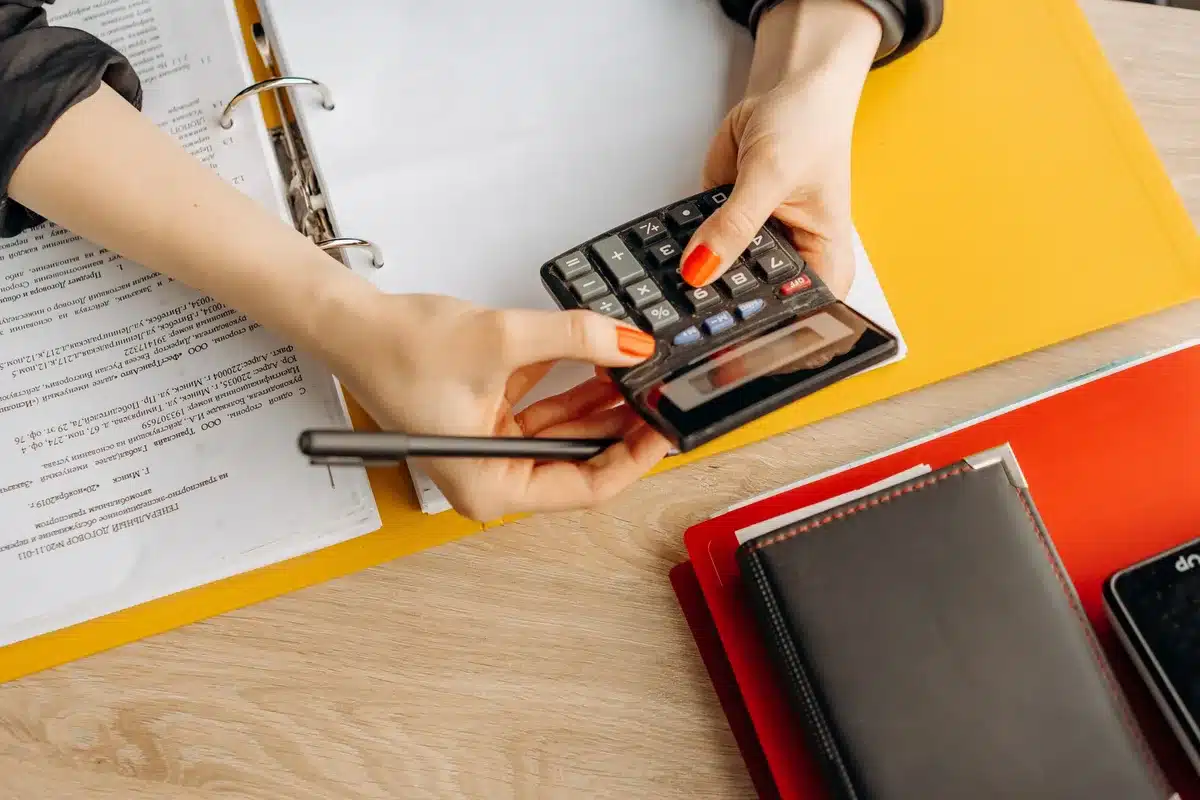Bureau avec registre comptable, calculatrice et dossiers organisés sous lumière douce