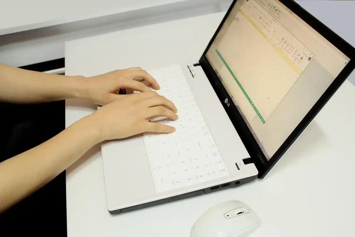 Personne devant un ordinateur portable signant des documents juridiques en ligne