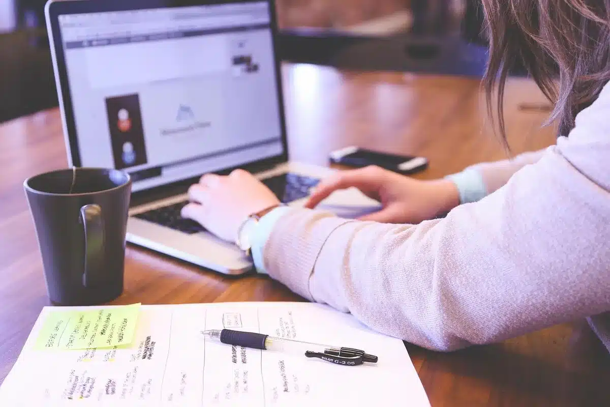 Bureau lumineux près d'une fenêtre avec ordinateur et documents, vue floue sur immeubles parisiens