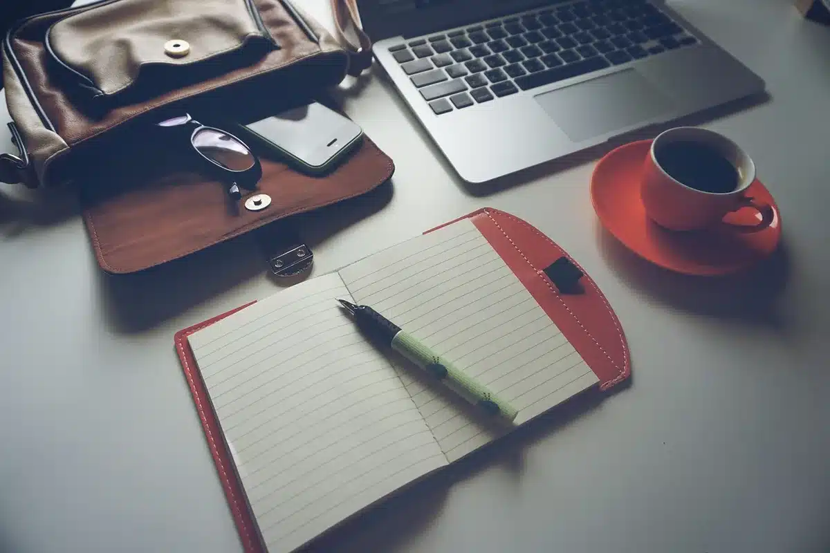 Mains anonymes sur un bureau près d'une fenêtre en pleine journée avec un ordinateur portable