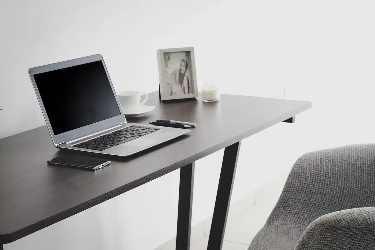 Poste de travail d'un micro-entrepreneur avec ordinateur et carnet sous la lumière du jour
